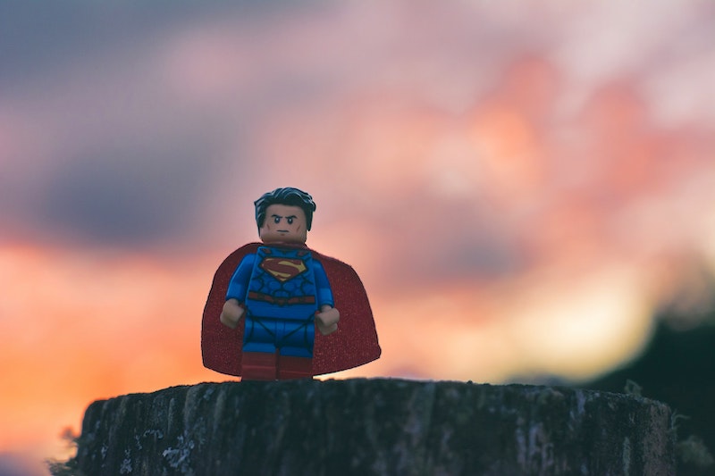 A Lego Superman proudly standing on a rock