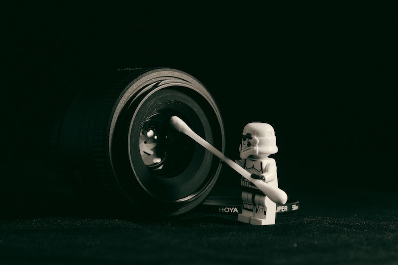 A Lego trooper cleaning the lens of a DSLR camera