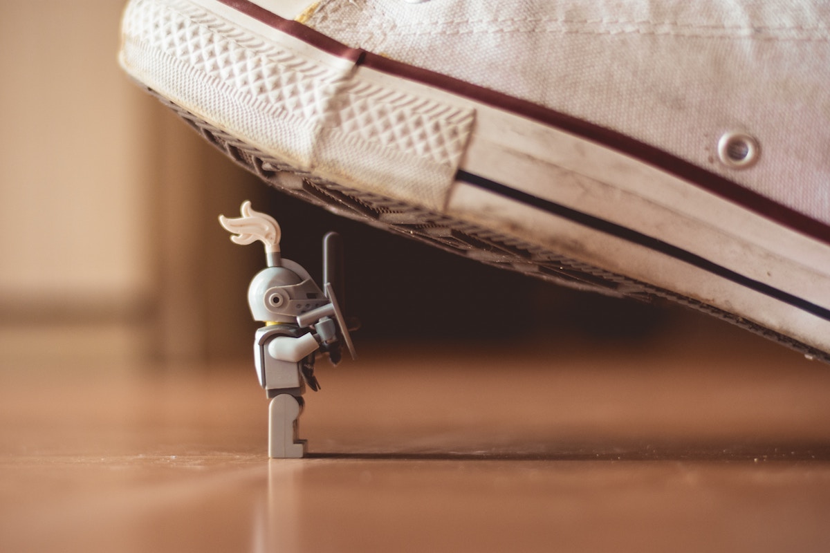 A Lego knight standing against a massive shoe